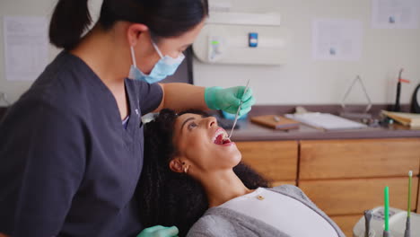 Zahnarzt-Mit-Gesichtsmaske-überprüft-Die-Zähne-Einer-Frau