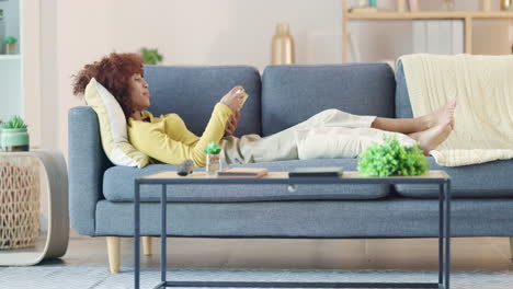 Relaxed-black-woman-reading-a-funny-book-on-a-sofa