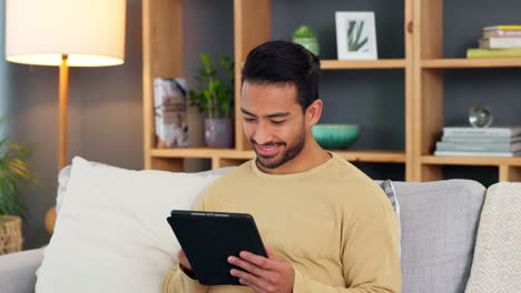Young-man-browsing-on-a-digital-tablet-on-a-sofa