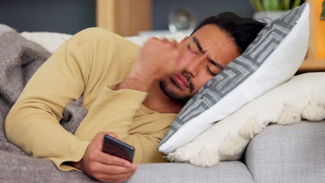 Sick-guy-using-a-phone-wrapped-in-a-blanket-lying