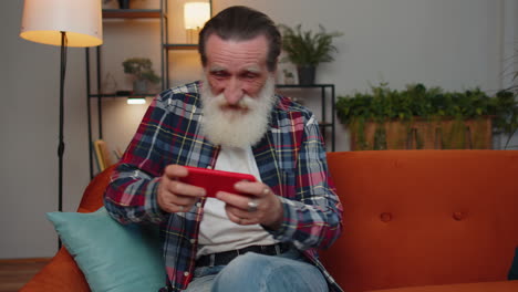 Besorgter-Lustiger-älterer-Alter-Großvater,-Der-Zu-Hause-Online-Rennvideospiele-Auf-Dem-Smartphone-Spielt