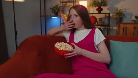 Mädchen-Sitzt-Auf-Der-Couch,-Isst-Popcorn-Und-Schaut-Sich-Zu-Hause-Interessante-Fernsehserien-Und-Sportspiele-Online-An