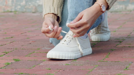 Hands-of-woman-tie-shoes-or-sneakers-on-pavement