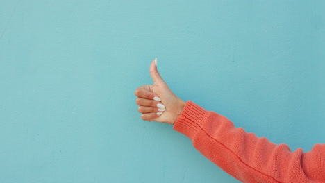 Thumbs-up,-thumb-or-hand-of-woman-on-blue-studio