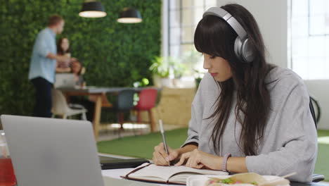 Headphones,-laptop-and-notebook-writing-for-woman