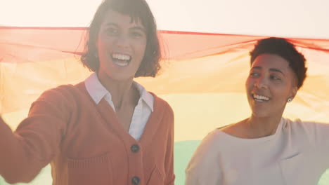 Lesbian-couple,-women-or-pride-flag-on-beach-date