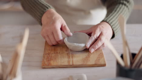 Clay-bowl,-woman-hands-and-sculpture-in-artist