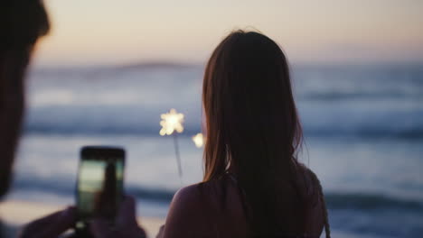 Phone,-beach-and-sparkler-with-a-woman-recording