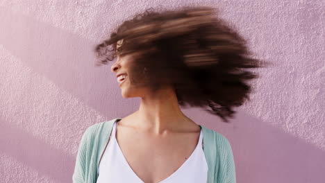 Funky-woman-shaking-natural-curly-hair-on-pink
