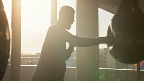 Man,-boxer-and-punching-boxing-bag-in-sunset
