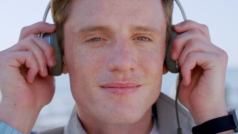Face,-music-headphones-and-man-at-beach-listening