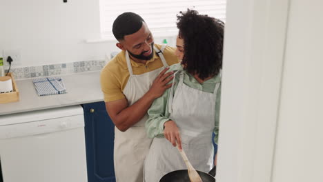 Love,-black-couple-talking-and-cooking-in-kitchen