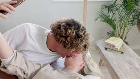 Couple,-selfie-and-lying-on-bed-while-kissing