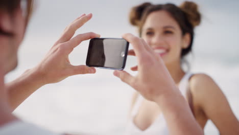 Couple,-bonding-and-phone-picture-on-beach-summer