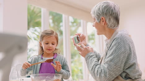 Baking,-girl-and-grandmother-with-smartphone