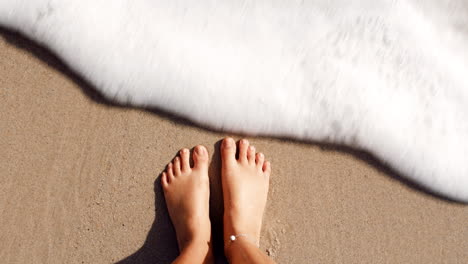 Top-view,-beach-and-person-feet-in-waves