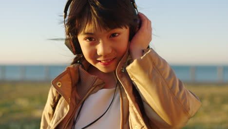 Face,-music-headphones-and-Asian-kid-at-beach-park