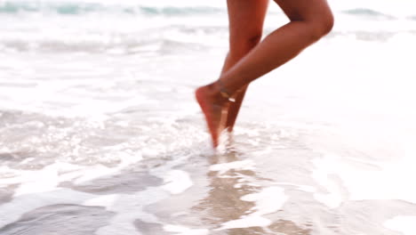 Legs,-beach-and-woman-relax-with-feet-in-water