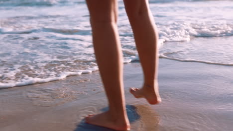 Woman,-beach-and-feet-walking-along-ocean