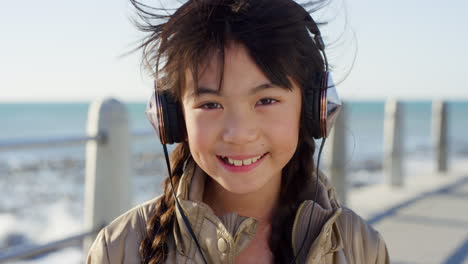 Girl-child,-face-and-headphones-at-beach-promenade