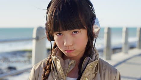 Sad,-headphones-and-face-of-Asian-girl-by-ocean