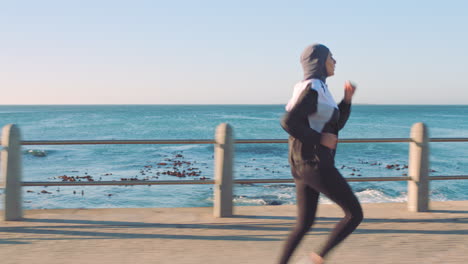 Muslim-woman,-running-or-fitness-by-ocean