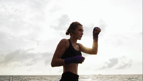 Athletische-Junge-Frau,-Die-Am-Meer-Gegen-Ihren-Sohn-Schattenboxen-Macht.-Schöne-Boxerin,-Die-Morgens-Am-Strand-Trainiert