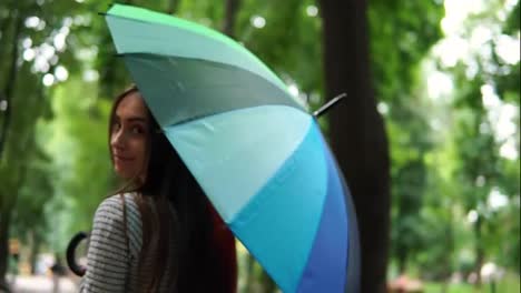 Rückansicht-Einer-Attraktiven-Frau,-Die-An-Einem-Regnerischen-Tag-Im-Stadtpark-Ihren-Bunten-Regenschirm-Dreht