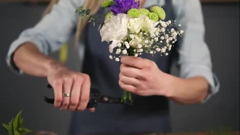 Close-Up-view-of-hands-of-professional-female-floral-artist-preparing-a-bouquet,-florist-cutting-flower-stems-at-flower-shot
