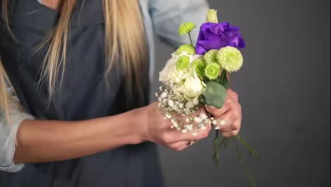 Slow-Motion-shot-of-hands-of-professional-blonde-female-floral-artist-arranging-beautiful-bouquet-at-flower-shot.-Floristry