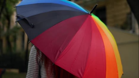 Close-Up-view-of-and-open-spinning-colourful-rainbow-umbrella-in-female-hands.-Slow-Motion-shot