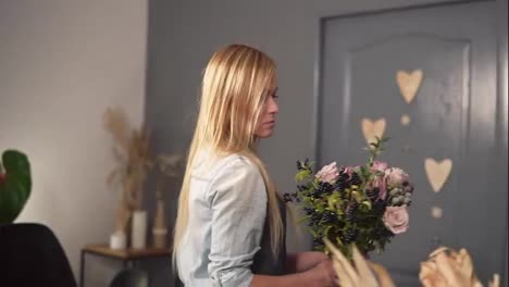 Young-female-florist-making-a-modern-bouquet-of-flowers.-She-is-putting-flowers-on-the-table.-Slow-Motion-shot