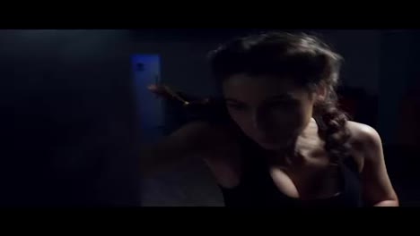 Beautiful-young-woman-punching-bag-in-dark-fitness-studio.-Boxing-in-Slow-Motion