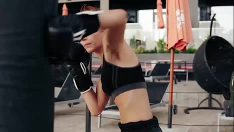 Strong-athletic-female-boxer-in-gloves-punching-a-bag.-Workout-outside.-Female-boxer-training.-Self-defence-concept