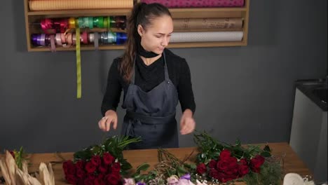 Junge-Floristin-Arrangiert-Einen-Modernen-Blumenstrauß-Mit-Wunderschönen-Roten-Rosen-Bei-Der-Blumenaufnahme.-Zeitlupenaufnahme