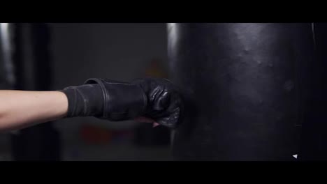 Close-Up-view-of-a-woman's-hand-in-boxing-gloves-punching-a-bag-in-a-boxing-club.-Slow-Motion-shot