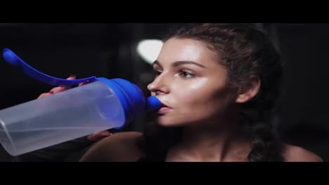 Sportliches-Mädchen,-Das-Nach-Dem-Training-Im-Fitnessstudio-Durstig-Aus-Einer-Wasserflasche-Trinkt.-Zeitlupenaufnahme