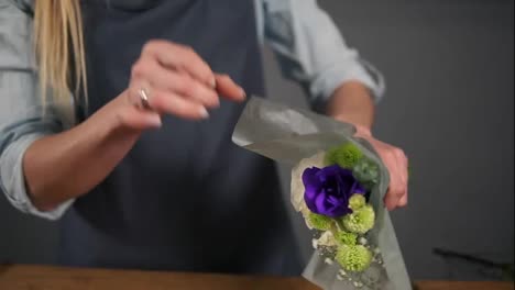 Close-Up-view-of-hands-of-female-florist-wrapping-a-bunch-of-flowers-in-decorating-paper.-Slow-Motion-shot
