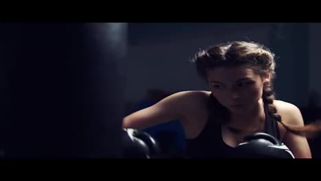 Beautiful-tanned-woman-punching-bag-in-fitness-studio.-Boxing-in-Slow-Motion