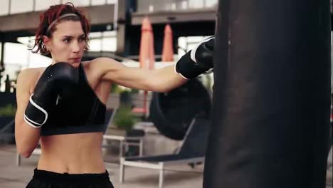 Beautiful-female-boxer-punching-a-bag-outside.-Workout-outside.-Female-boxer-training