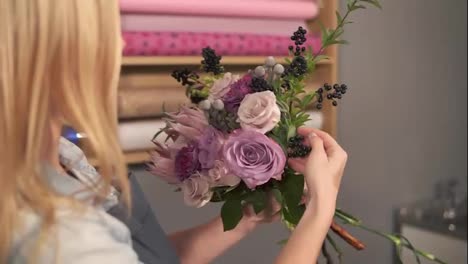 Side-view-of-female-blonde-florist-arranging-modern-bouquet-and-looking-how-the-flowers-are-combined.-Handsome-flower-shot-owner