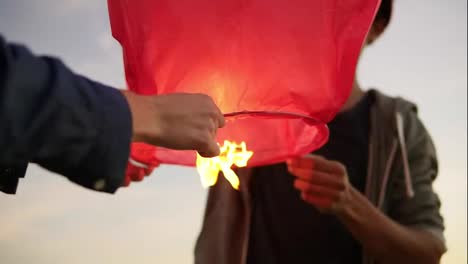 Close-Up-view-of-young-multi-ethnic-couple-holding-red-paper-lantern-before-launching.-Attractive-woman-with-her-african-boyfriend