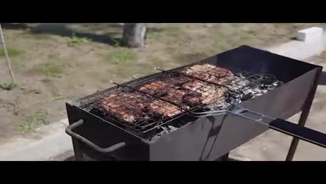 Meat-grilled-on-the-grid.-Food-for-barbecue-party.-Male-hand-is-splashing-water-to-eliminate-fire-and-turning-the-grid-around