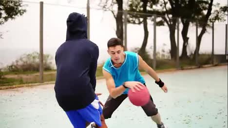 Two-young-multi-ethnic-friends-play-basketball-on-the-street.-One-guy-gets-a-ball-in-the-basket.-Slow-Motion-shot