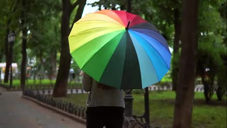 Vista-Posterior-De-Una-Mujer-Irreconocible-Caminando-Con-Un-Paraguas-Colorido-En-Un-Día-Lluvioso-En-El-Parque-De-La-Ciudad