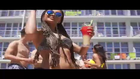 Young-beautiful-girl-with-dreads-and-sunglasses-coming-closer-to-camera-while-dancing-on-the-pool-party.-Happy-friends-in