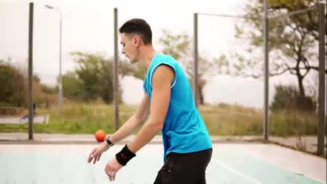 Man-throwing-basketball-ball-on-court-in-park,-slow-motion-shot