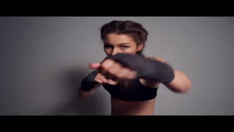 Close-Up-view-of-a-young-woman-training-with-her-hands-wrapped-in-boxing-tapes-and-looking-in-the-camera.-Boxing-in-Slow-Motion