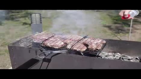 Meat-grilled-on-the-grid.-Food-for-barbecue-party.-Male-hand-is-splashing-water-to-eliminate-fire.-Meat-on-a-grill.-shot-in-4k