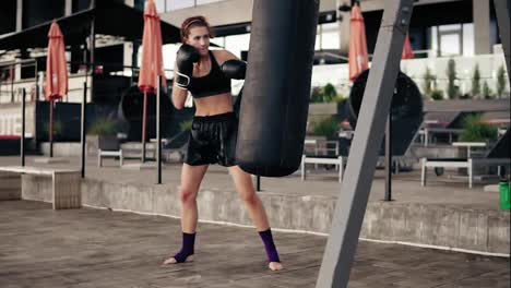 Female-boxer-exercising-outdoors.-Beautiful-athletic-woman-in-gloves-punching-a-bag-outside.-Self-defence-concept.-Slow-Motion